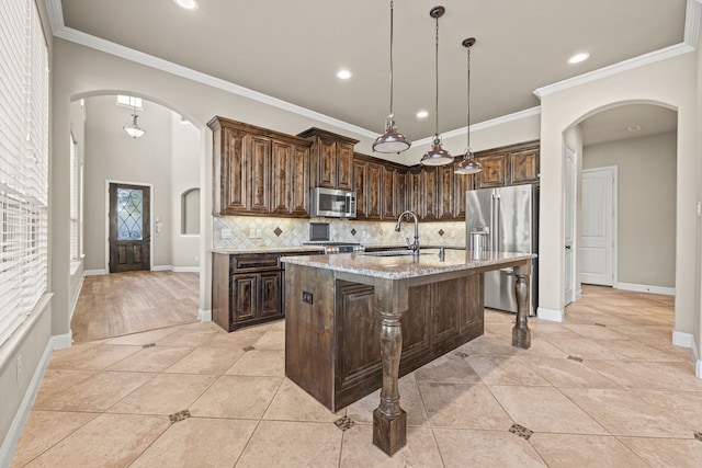 kitchen featuring light stone countertops, sink, stainless steel appliances, an island with sink, and light tile patterned floors