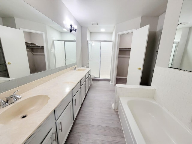 bathroom with vanity and shower with separate bathtub