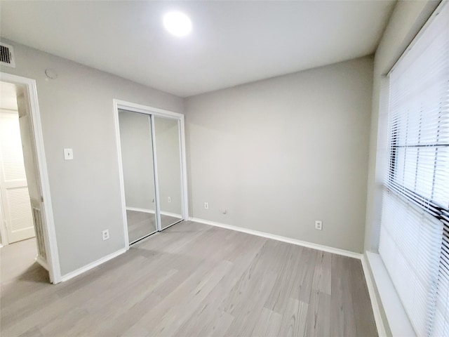 unfurnished bedroom featuring light wood-type flooring and a closet