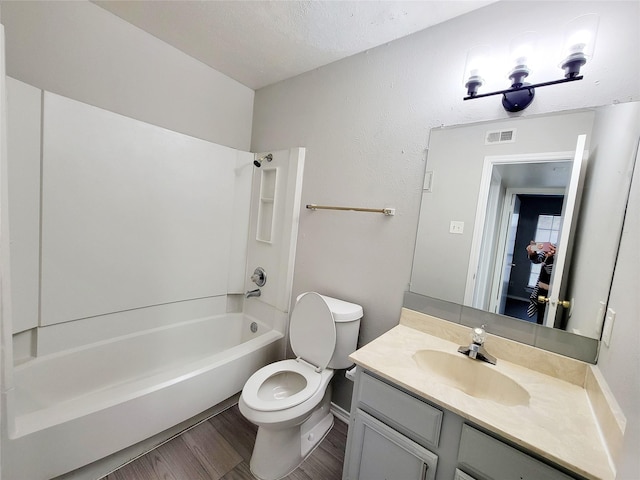 full bathroom featuring vanity, a textured ceiling, shower / washtub combination, hardwood / wood-style flooring, and toilet