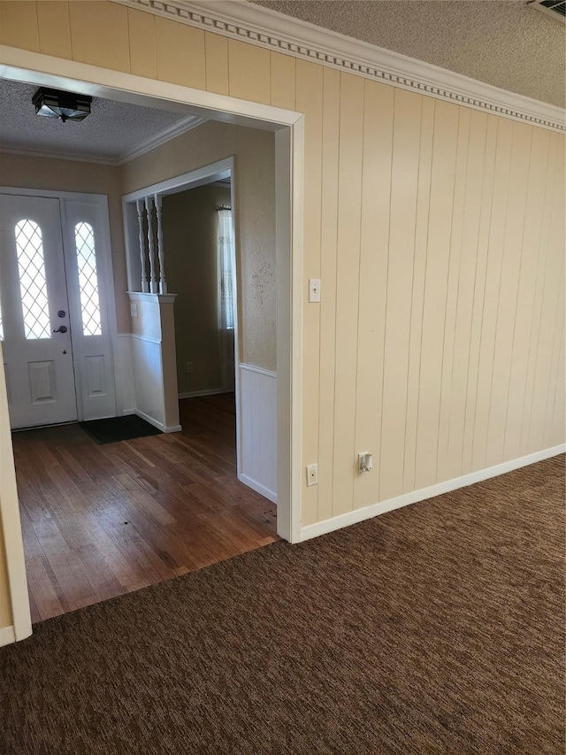 carpeted entrance foyer featuring crown molding and a textured ceiling