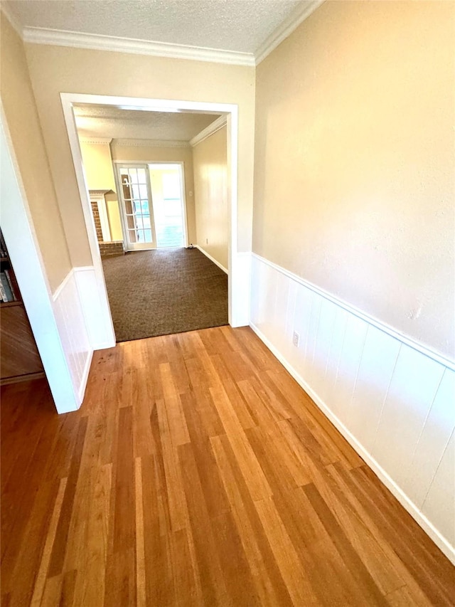 hallway featuring crown molding, hardwood / wood-style floors, and a textured ceiling