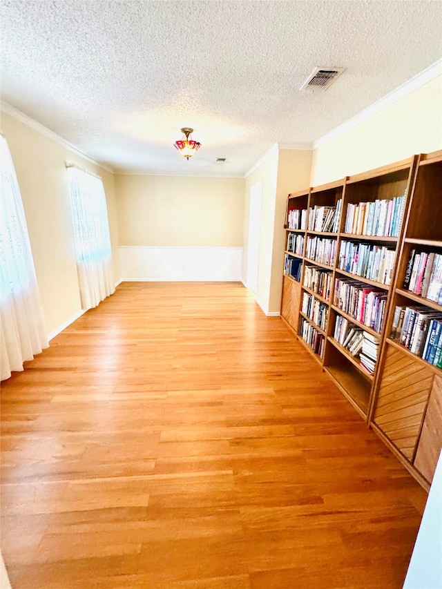 unfurnished room with ornamental molding, light hardwood / wood-style flooring, and a textured ceiling