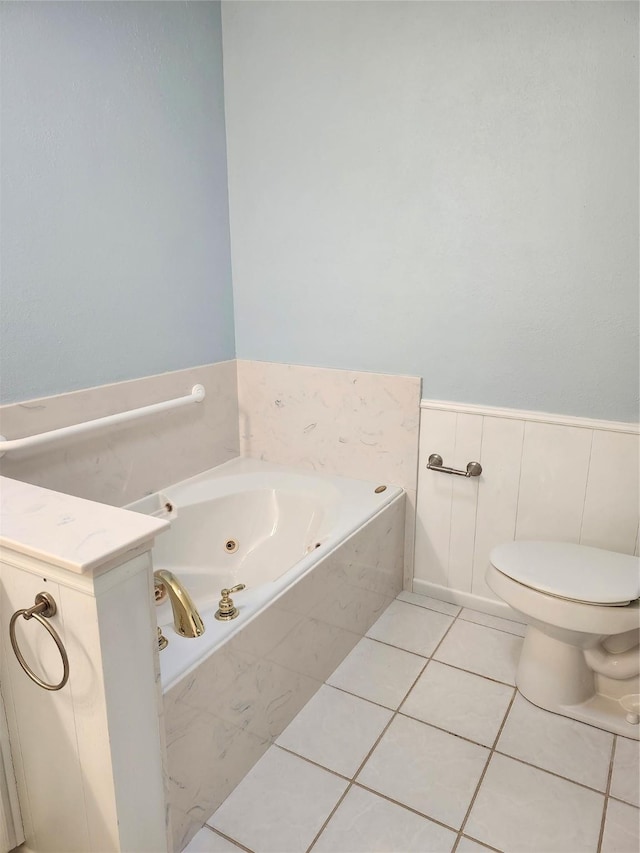 bathroom with tile patterned flooring, tiled tub, and toilet