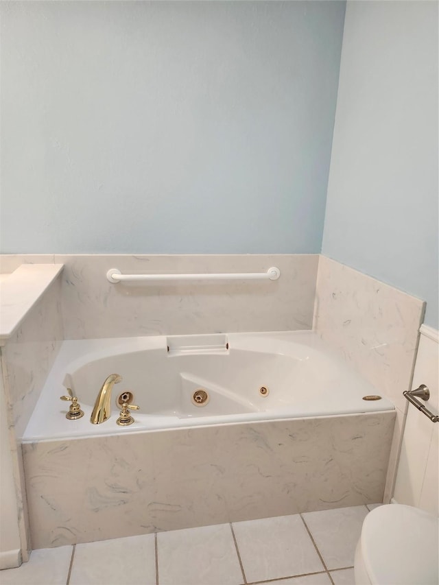 bathroom featuring tile patterned flooring, a relaxing tiled tub, and toilet