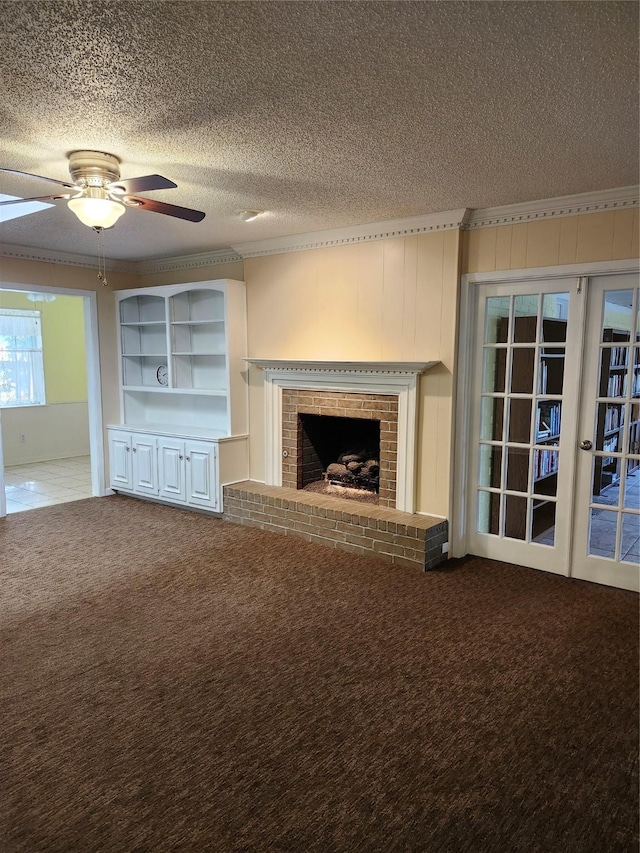 unfurnished living room with french doors, a textured ceiling, ornamental molding, carpet floors, and a fireplace