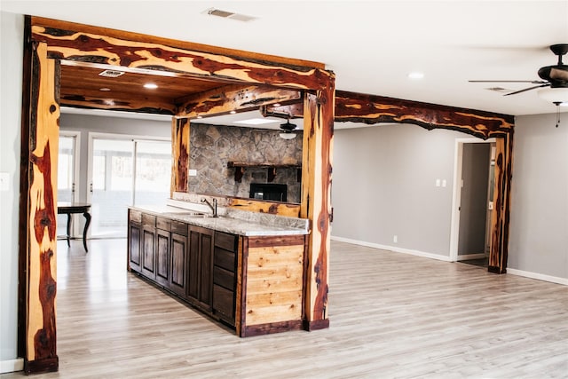 kitchen with dark brown cabinetry, sink, ceiling fan, and light wood-type flooring