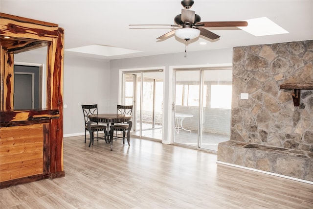 dining space featuring ceiling fan, a wealth of natural light, light hardwood / wood-style floors, and a skylight