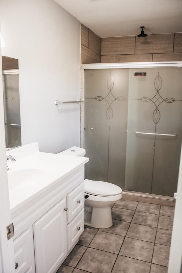 bathroom featuring an enclosed shower, vanity, tile patterned flooring, and toilet