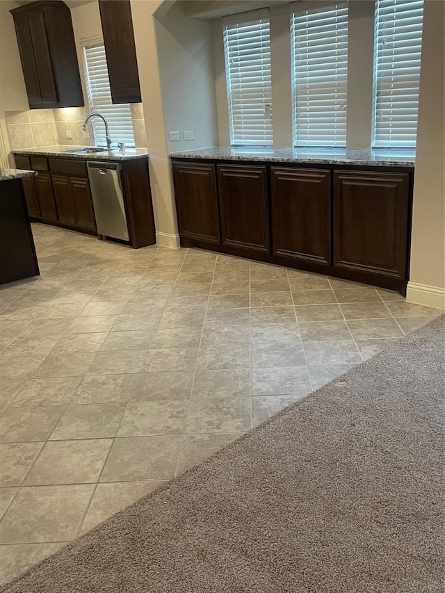 kitchen featuring backsplash, light stone counters, stainless steel dishwasher, sink, and light tile patterned flooring