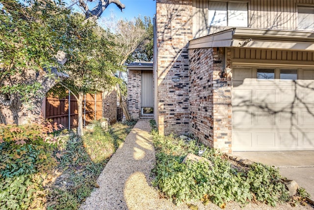 property entrance featuring a garage, fence, and brick siding