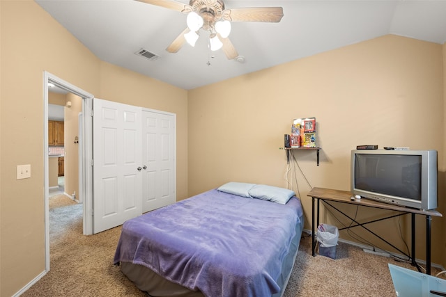 carpeted bedroom with ceiling fan, a closet, and vaulted ceiling