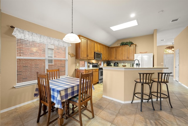 kitchen featuring stainless steel appliances, vaulted ceiling, decorative light fixtures, a kitchen island with sink, and light tile patterned floors