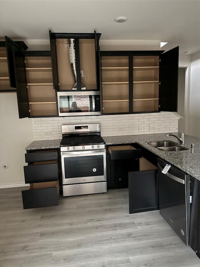 kitchen featuring stone counters, light wood-type flooring, appliances with stainless steel finishes, and tasteful backsplash