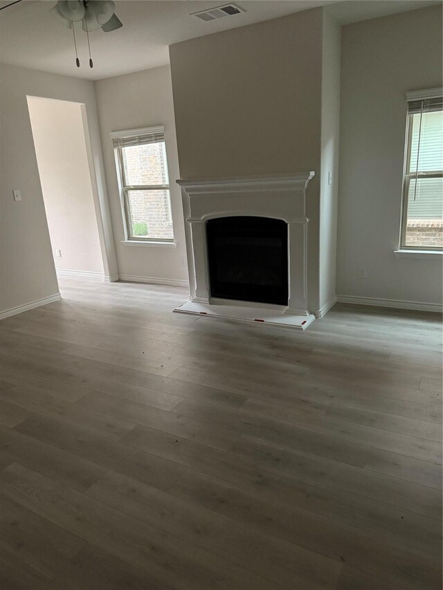 unfurnished living room featuring ceiling fan and hardwood / wood-style flooring