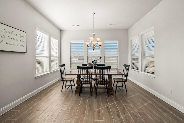 dining space featuring dark wood-type flooring and a chandelier