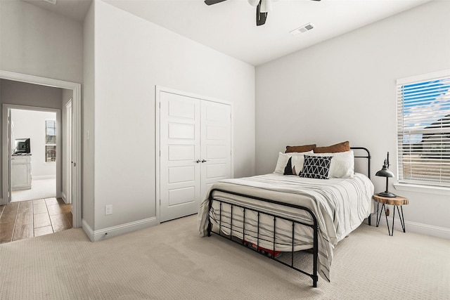 bedroom with ceiling fan, light colored carpet, and a closet