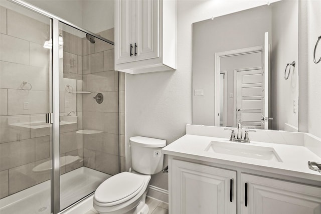 bathroom featuring vanity, a shower with shower door, and toilet