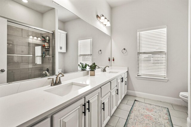 bathroom featuring toilet, vanity, tile patterned floors, and an enclosed shower