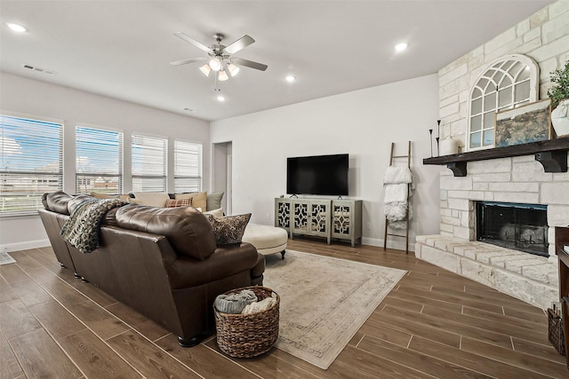 living room featuring a stone fireplace and ceiling fan