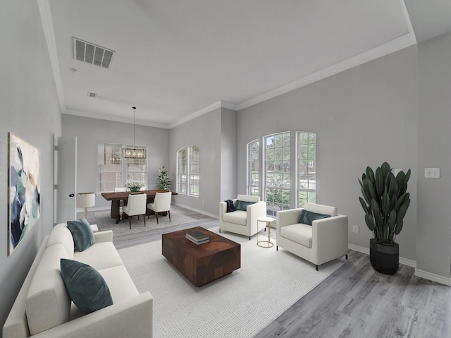 living room with baseboards, ornamental molding, visible vents, and light wood-style floors