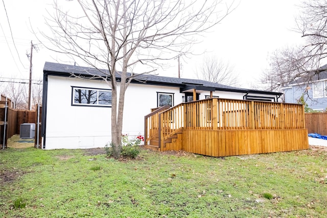 rear view of house with central AC unit, a deck, and a lawn