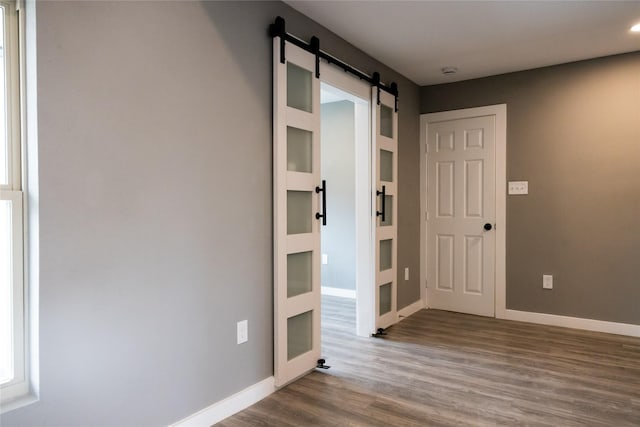 hallway with wood-type flooring and a barn door