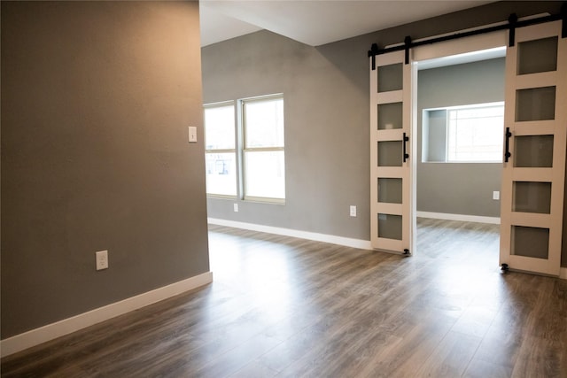 unfurnished room featuring a barn door and dark hardwood / wood-style floors