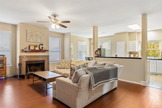 living room with ceiling fan, a wealth of natural light, wood-type flooring, and a tile fireplace