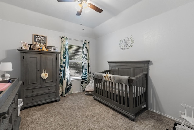 carpeted bedroom with vaulted ceiling, ceiling fan, and a crib