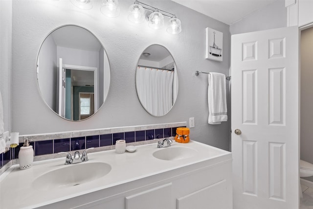 bathroom with backsplash, vanity, lofted ceiling, and toilet