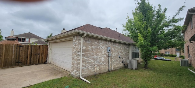 view of side of home featuring central AC unit, a garage, and a yard