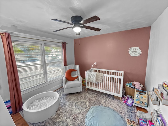 bedroom with ceiling fan and a nursery area