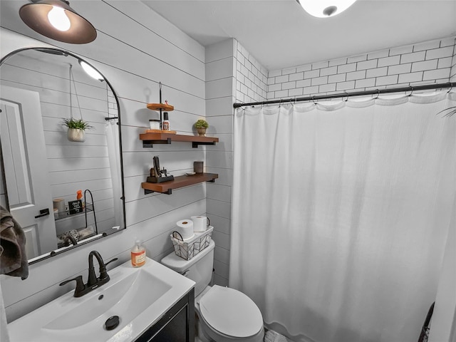 bathroom with vanity, wood walls, toilet, and walk in shower