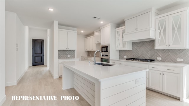 kitchen featuring white cabinets, a center island with sink, stainless steel appliances, and sink