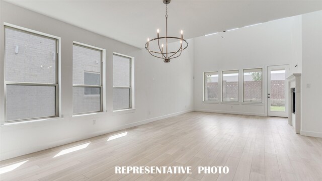 unfurnished room featuring a chandelier and light wood-type flooring