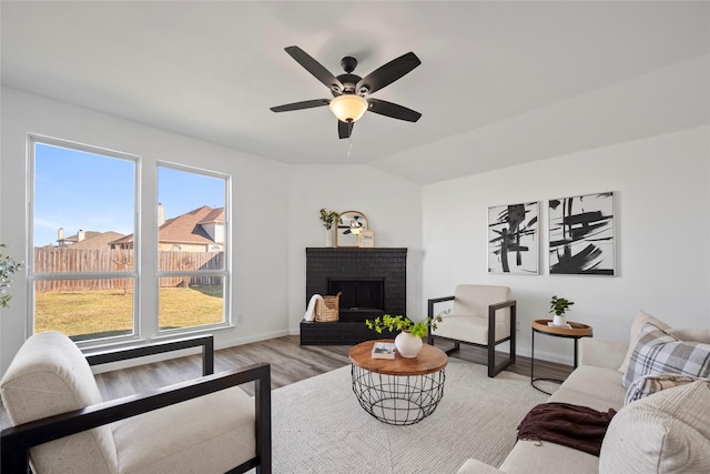 living room featuring plenty of natural light, light hardwood / wood-style floors, vaulted ceiling, and a brick fireplace