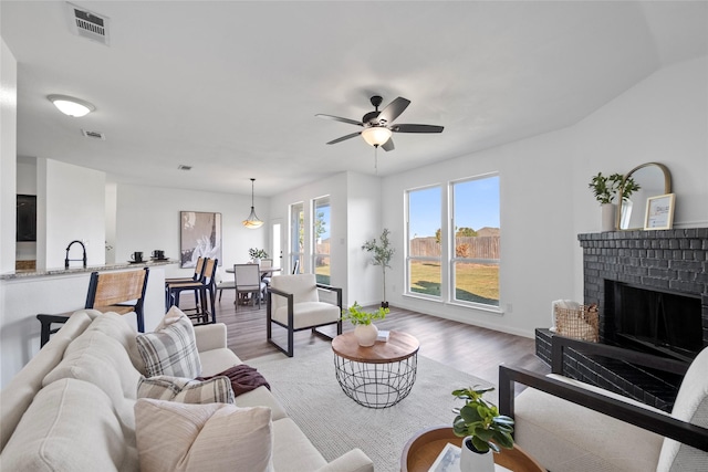 living room with ceiling fan, a fireplace, hardwood / wood-style floors, and sink