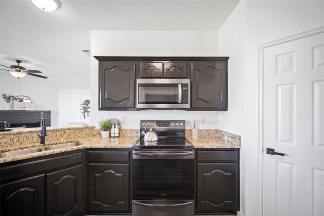 kitchen with ceiling fan, sink, light stone countertops, and stainless steel appliances