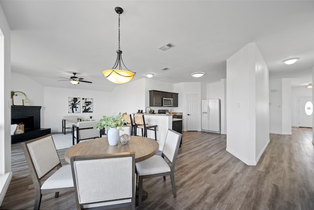 dining area with ceiling fan, a fireplace, and hardwood / wood-style flooring