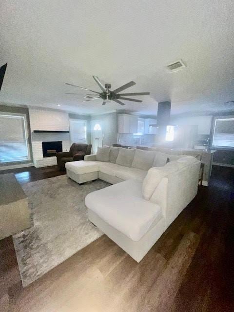 living room featuring ceiling fan, hardwood / wood-style flooring, and a textured ceiling