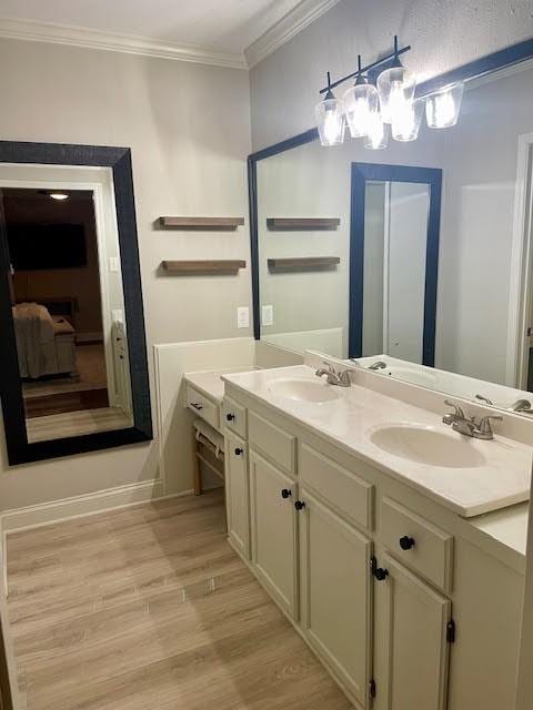 bathroom with hardwood / wood-style floors, vanity, crown molding, and a chandelier