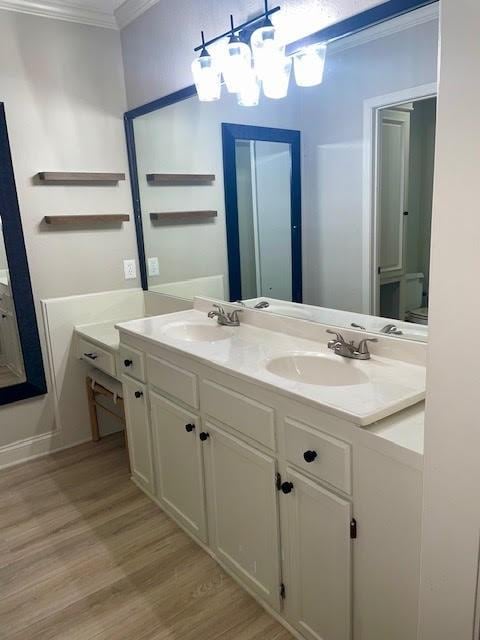 bathroom featuring vanity, hardwood / wood-style flooring, an inviting chandelier, and crown molding