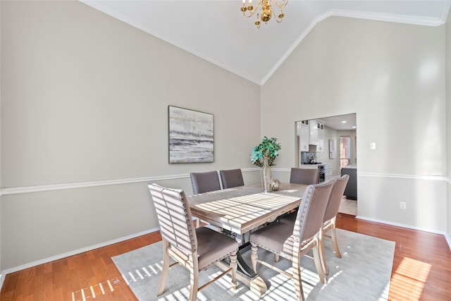 dining room with hardwood / wood-style floors, crown molding, high vaulted ceiling, and an inviting chandelier