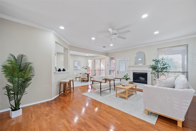 living room featuring light hardwood / wood-style flooring, ceiling fan, and ornamental molding