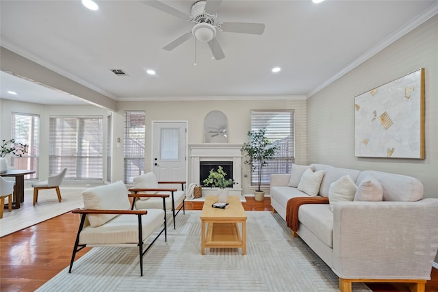 living room featuring light wood-type flooring, ceiling fan, and ornamental molding