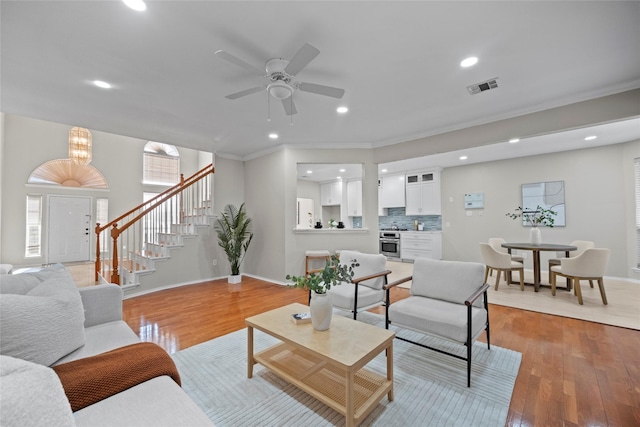 living room featuring ceiling fan with notable chandelier and light hardwood / wood-style flooring