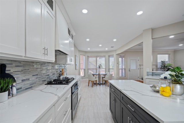 kitchen with premium range hood, light stone counters, tasteful backsplash, stainless steel appliances, and white cabinets