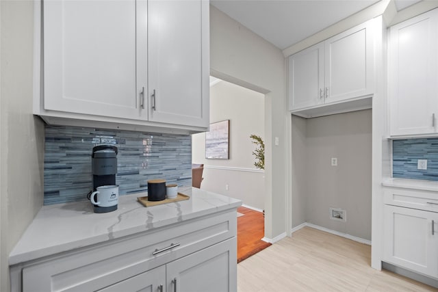 kitchen with white cabinets, light stone countertops, and tasteful backsplash