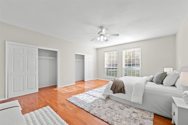 bedroom with multiple closets, ceiling fan, and light hardwood / wood-style floors